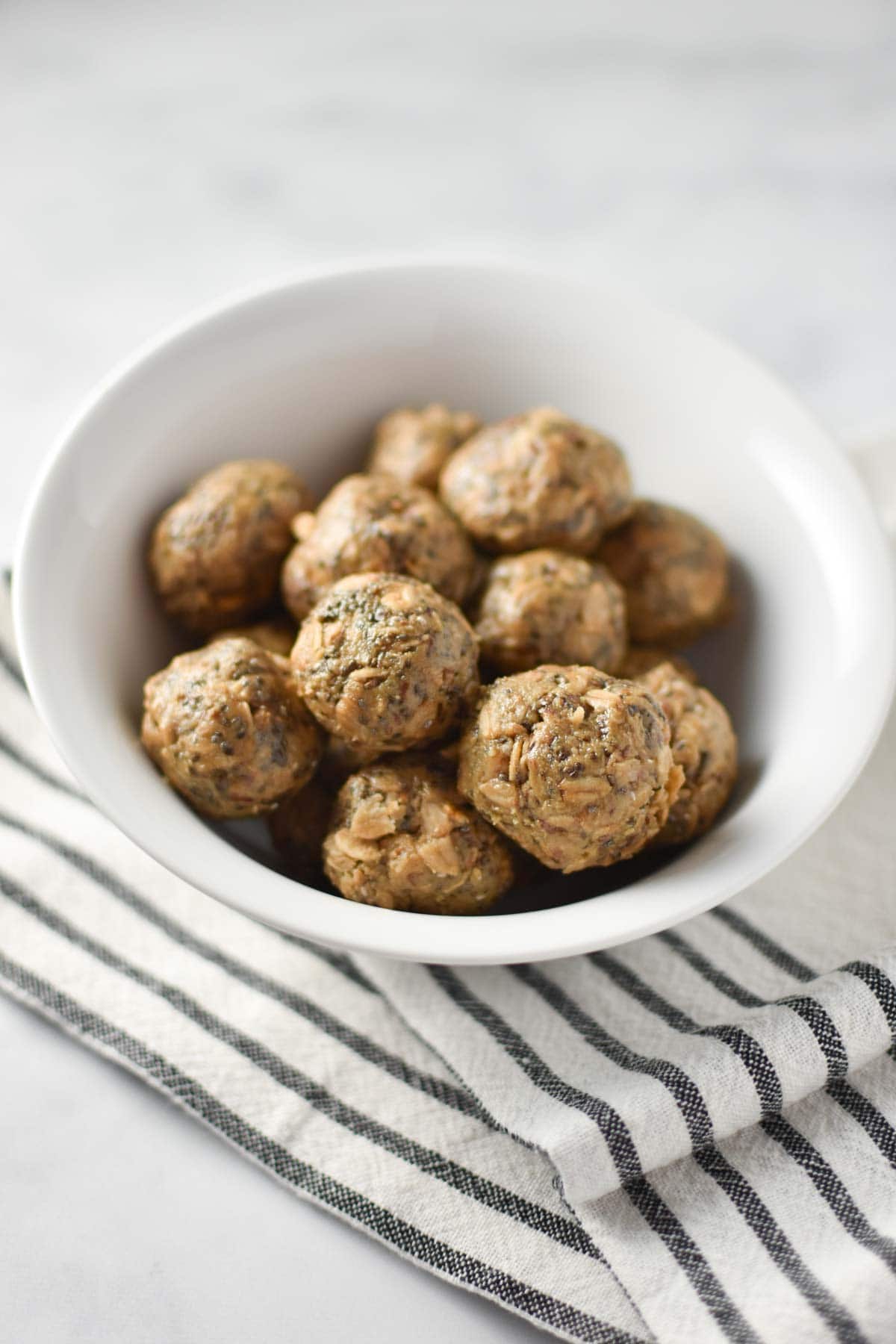 A bowl of sunbutter balls with oats and chia on a striped towel