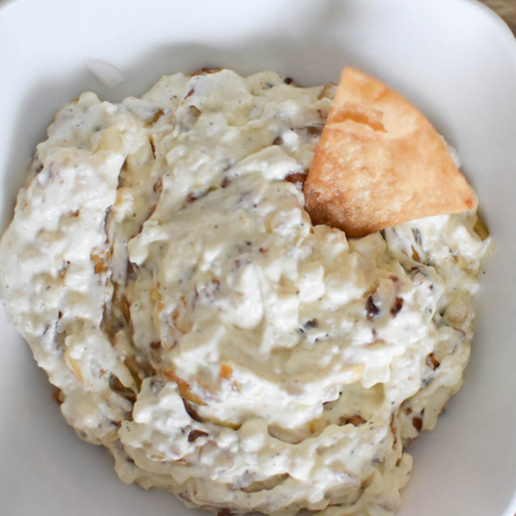 Caramelized shallot dip without sour cream in a white bowl with a chip