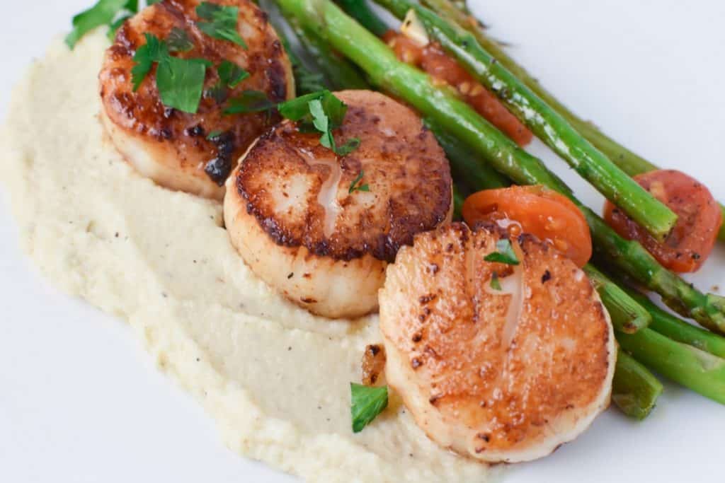 Scallops with chive oil, pureed cauliflower, and roasted asparagus. A great date night dinner or holiday meal #datenight #scallops #chives #asparagus #holidaymeal