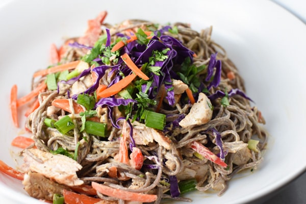 Soba noodles with carrots, cabbage, and green onion in a white bowl