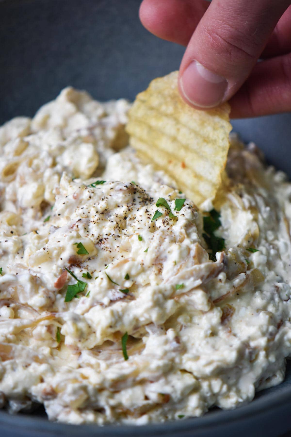 Dipping a potato chip into a bowl of shallot dip