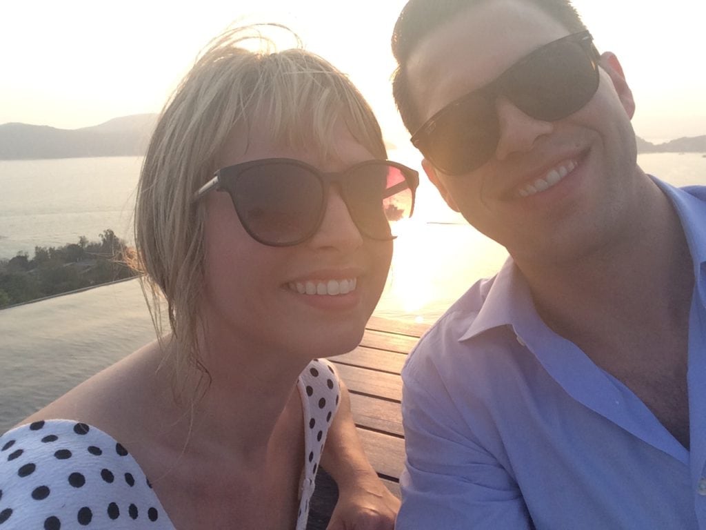 A man and women smiling with the ocean in the background