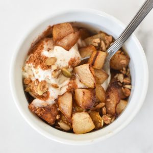 A spoon dipping into a healthy pear crumble topped with cinnamon