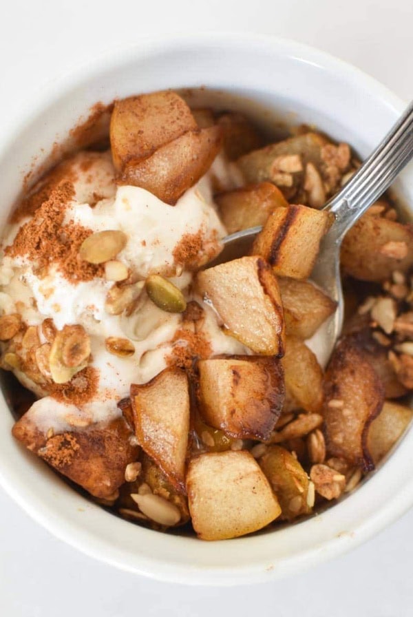 A spoon dipping into a healthy pear crumble topped with cinnamon