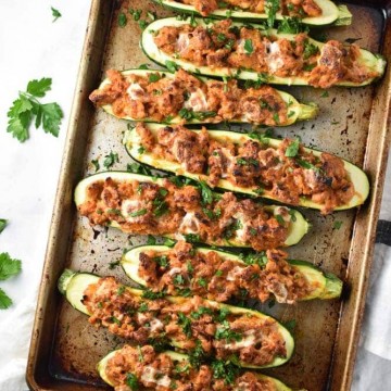 A row of zucchini boats neatly stacked on a baking sheet