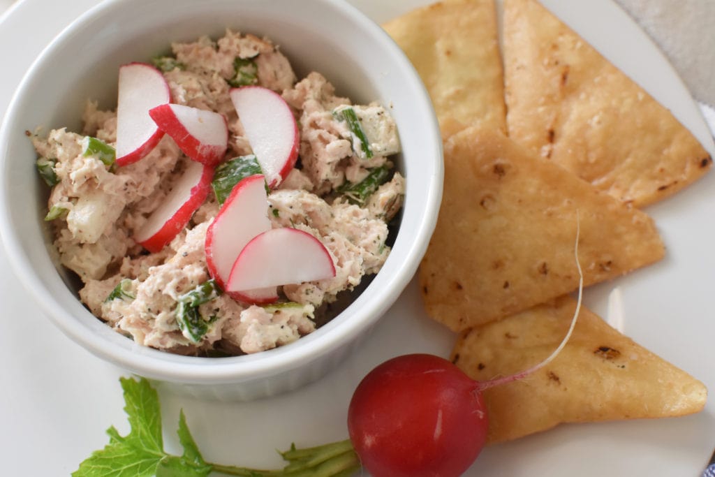 Tuna salad in a white bowl with pita chips and radishes