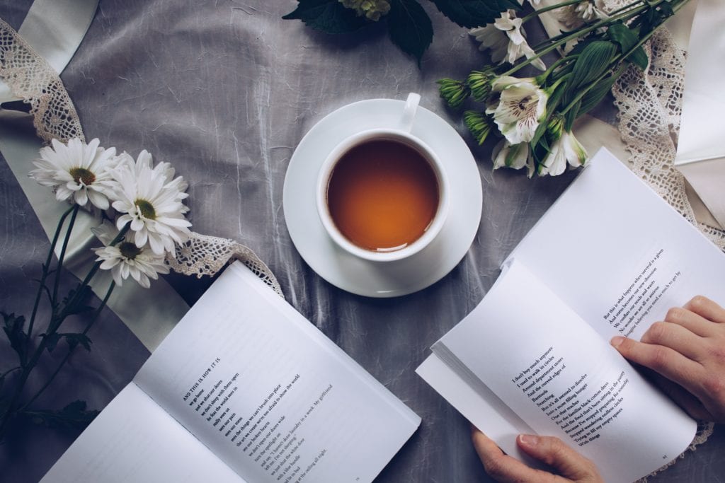 A cup of ginger turmeric tea on a blanket with books.