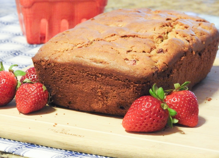 Strawberry bread on a board with a pint of strawberries