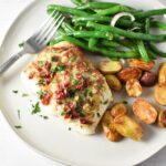 A filet of mediterranean halibut on a white plate with potatoes and green beans