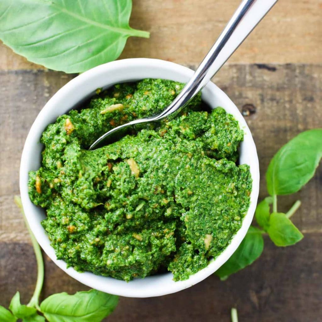 A spoon scooping bright green sunflower seed pesto