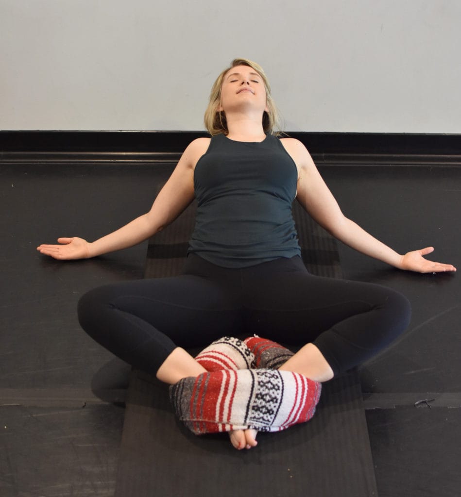 A woman doing a supported savasana pose for restorative yoga