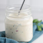A jar of gluten free ranch dressing with a whisk.