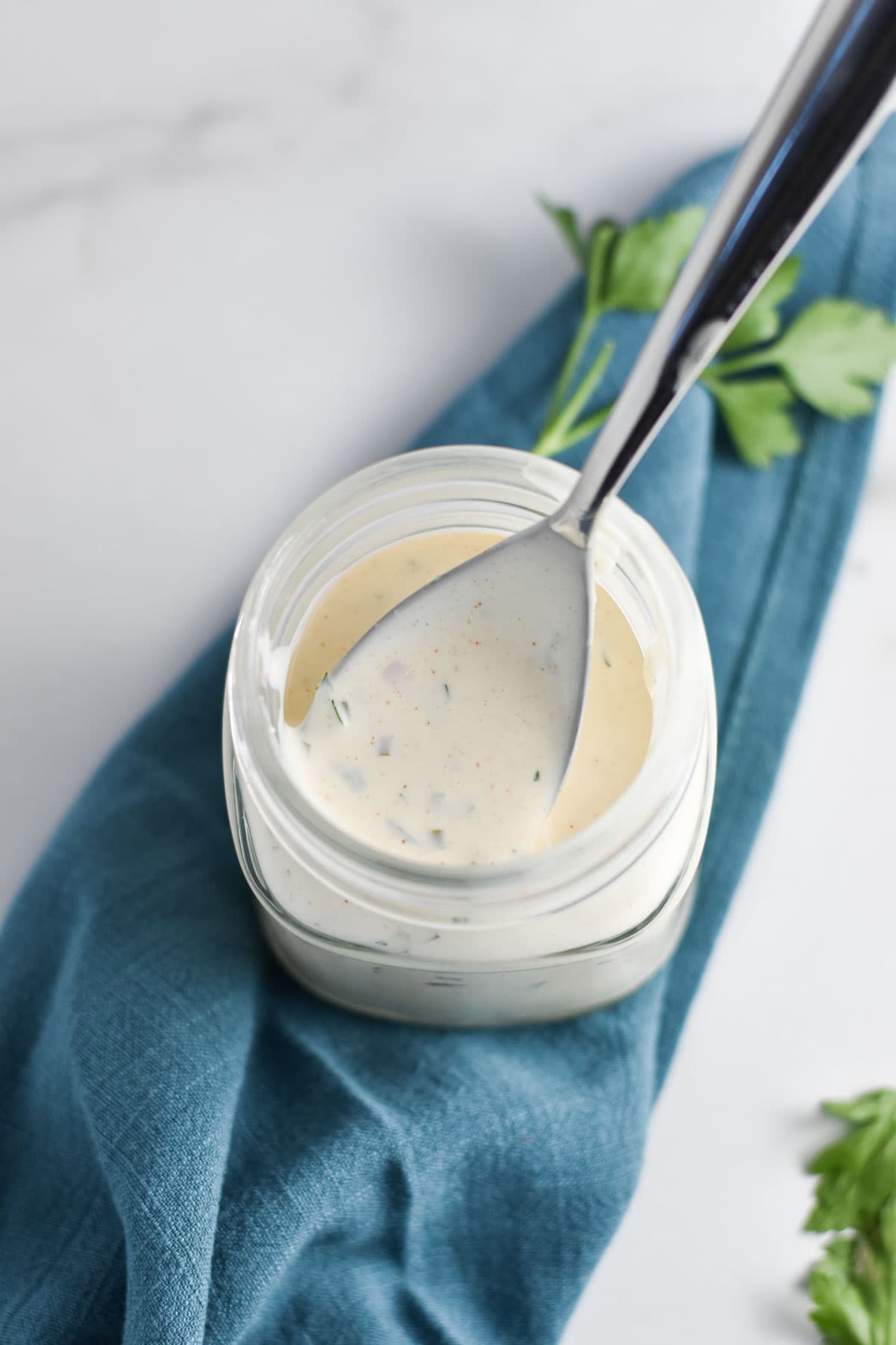 A spoon dipping into ranch dressing.
