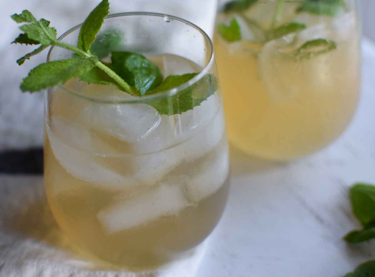 Two glasses of pear juice and mint sticking out of them.