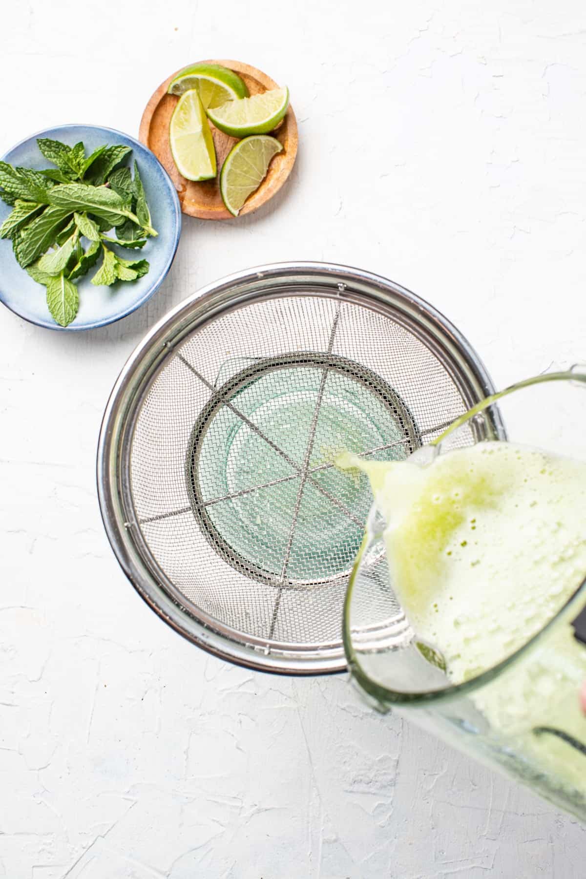 Pouring the pear juice mixture into a fine mesh strainer.