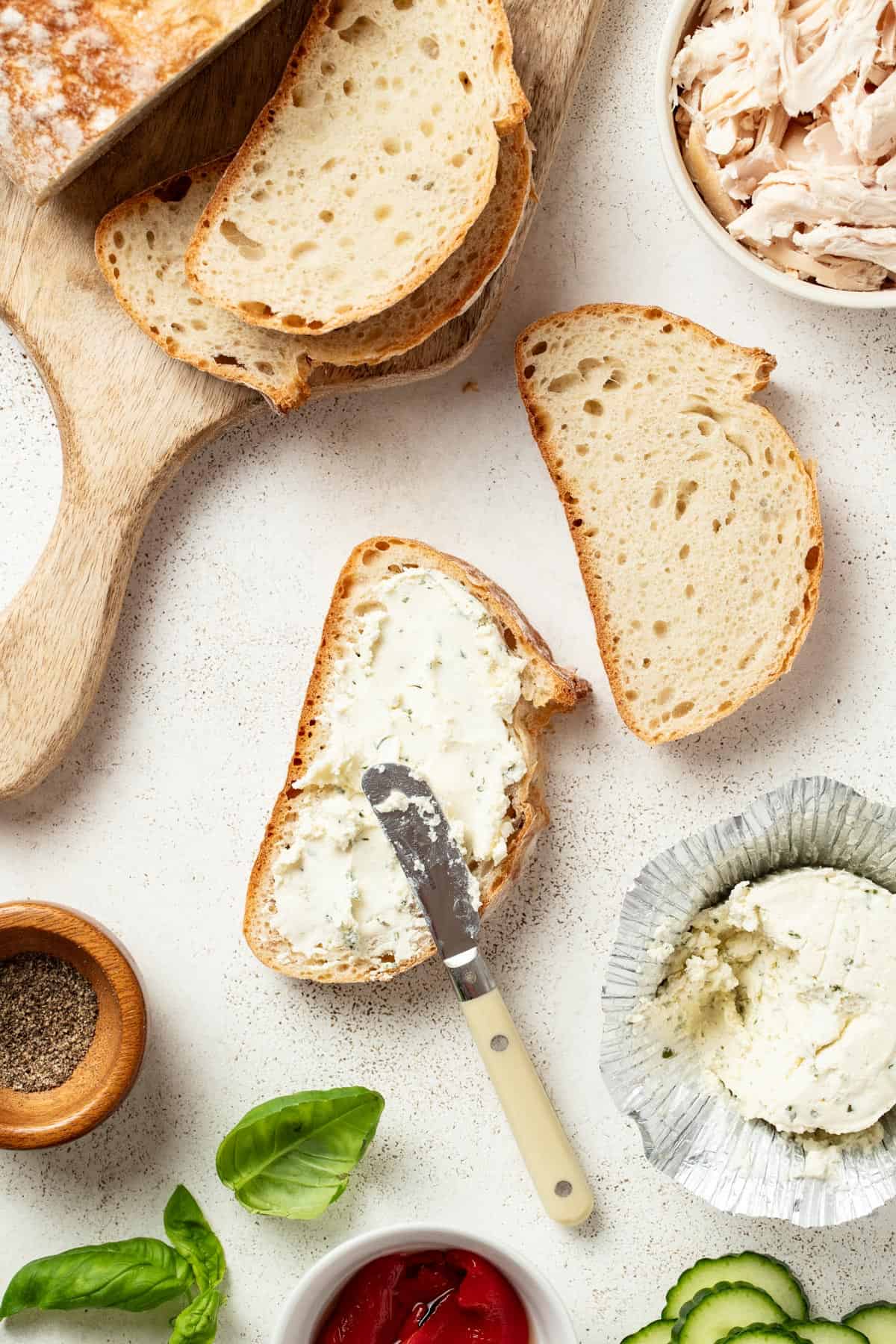 Spreading Boursin cheese to both sides of the sandwich bread.