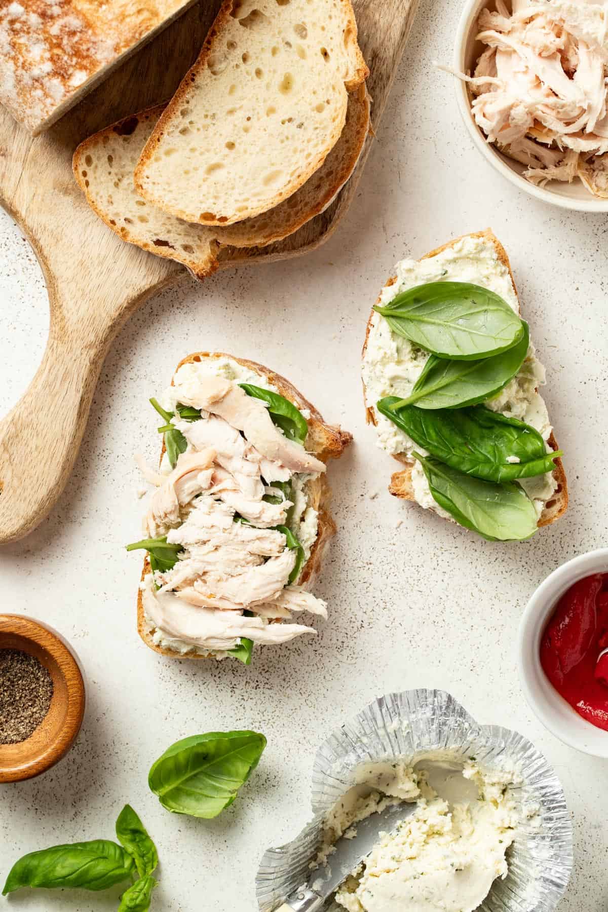 Layering shredded rotisserie chicken onto the top of the sandwich.