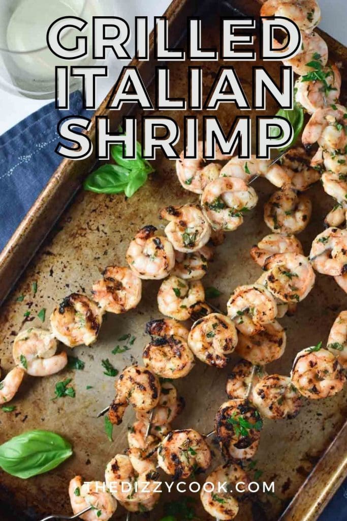 Grilled Italian Shrimp on skewers on a white table with a glass of white wine