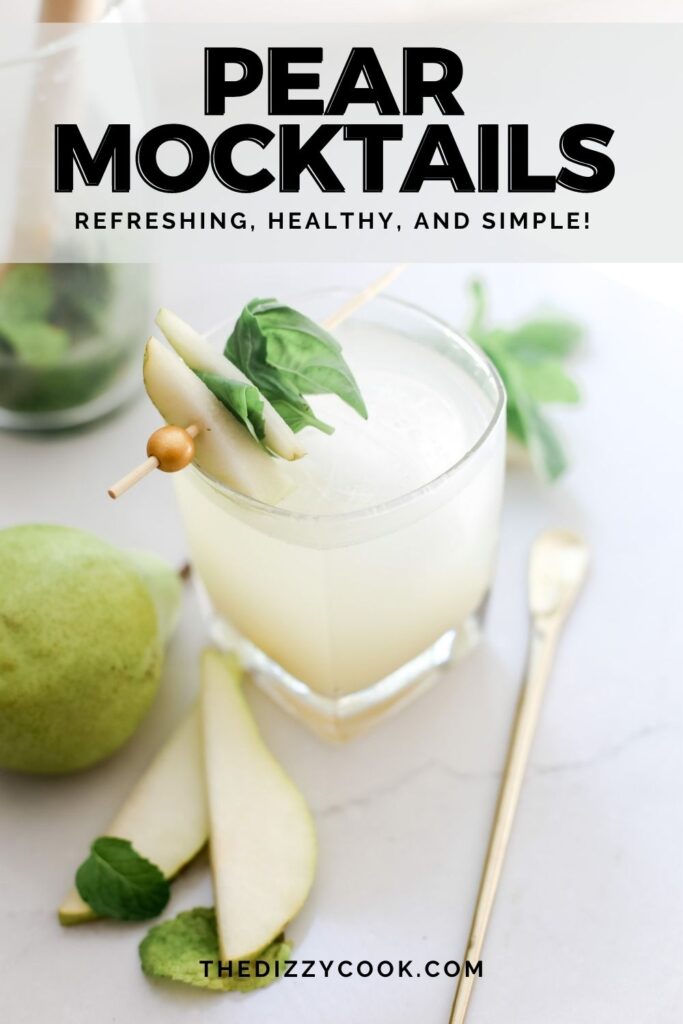 A pear mocktail topped with basil and mint on top of a white table.