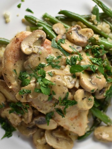 Chicken with mushrooms and green beans on a grey plate with a blue napkin