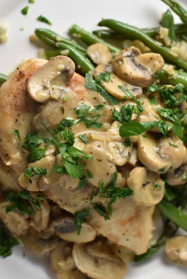 Chicken with mushrooms and green beans on a grey plate with a blue napkin