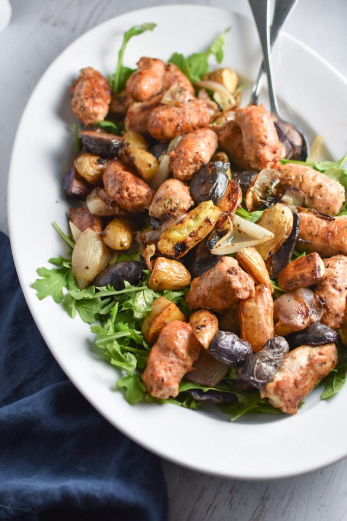 Looking for an easy, one pan dinner? This salad with arugula is topped with sweet roasted shallots, potatoes, and chicken sausage for the perfect, healthy fall meal that's gluten free and whole 30 #healthy #weeknightdinner #migrainediet