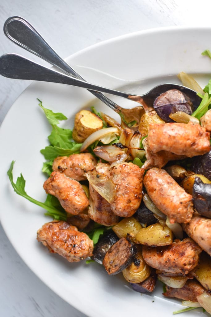 Looking for an easy, one pan dinner? This salad with arugula is topped with sweet roasted shallots, potatoes, and chicken sausage for the perfect, healthy fall meal that's gluten free and whole 30 #healthy #weeknightdinner #migrainediet