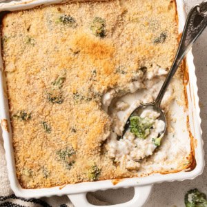 A white baking dish with a cheesy broccoli rice casserole inside.