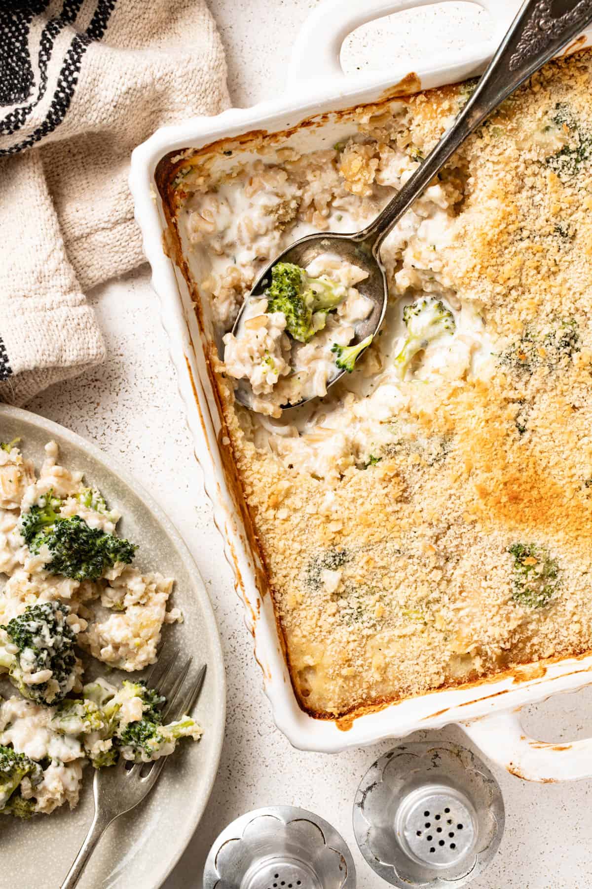 Broccoli rice casserole being spooned onto a white serving plate.