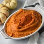 A full dish of sweet potatoes with paprika on top on a white table