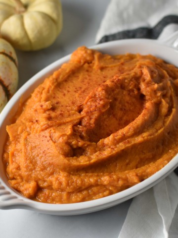 A full dish of sweet potatoes with paprika on top on a white table