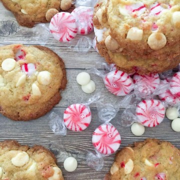 White chocolate and peppermint cookies on a wooden table with peppermint candies and white chocolate pieces