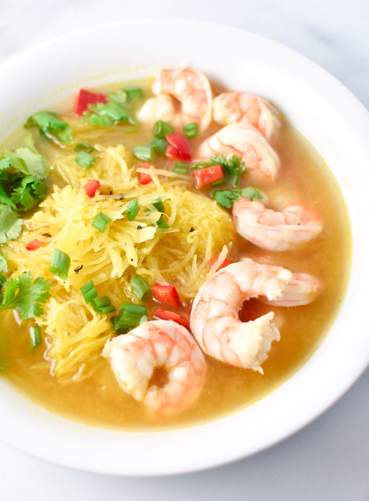 Spaghetti squash soup with shrimp in a white bowl on a marble table