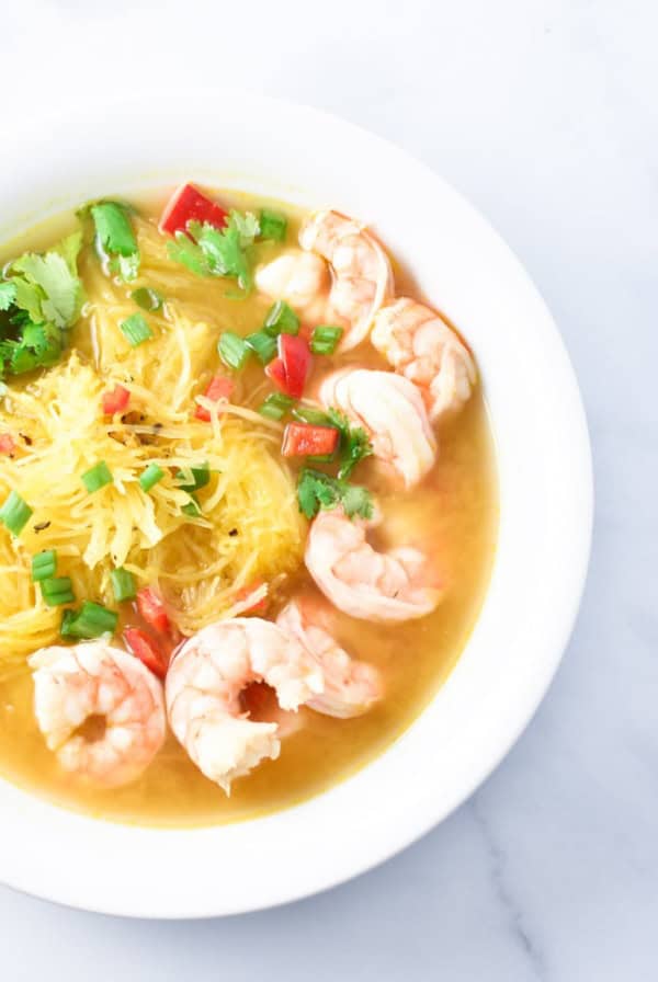 A white bowl filled with spaghetti squash soup on a white table
