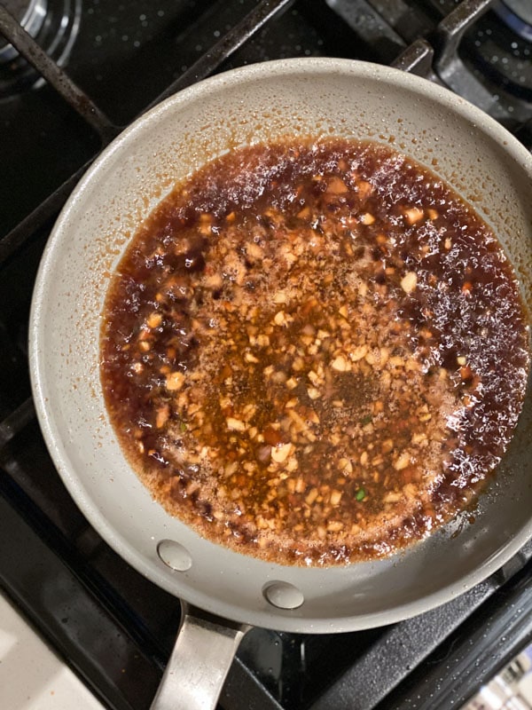 Simmering sesame ginger sauce for chicken wings in a saute pan
