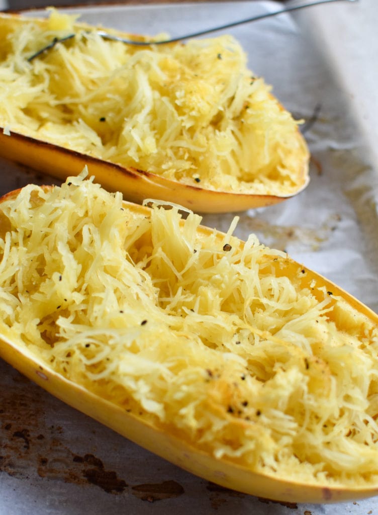 Two spaghetti squash on a tray with parchment paper