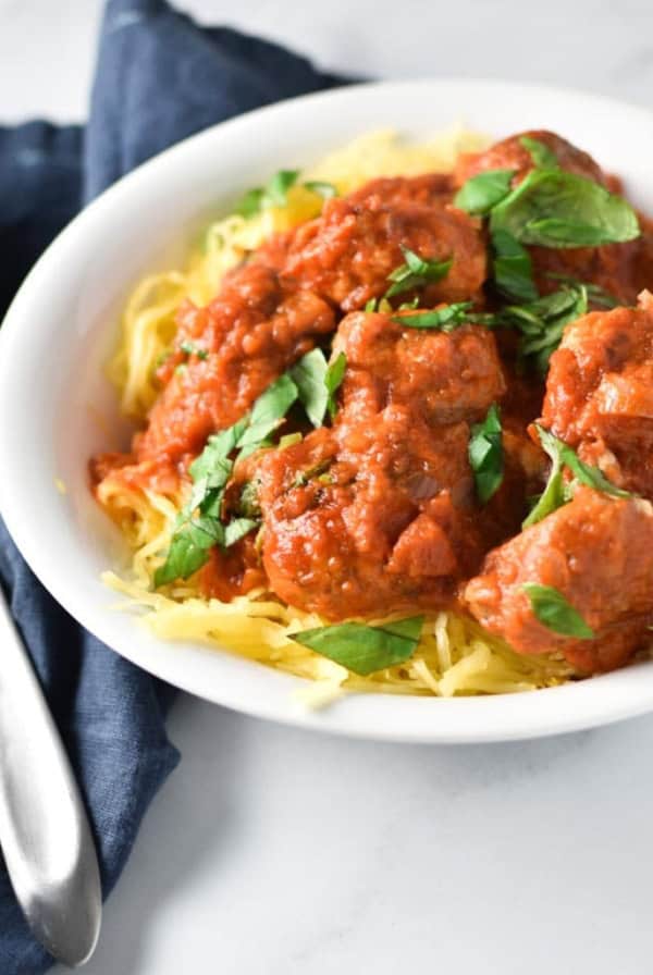A white bowl of spaghetti squash with meatballs and marinara sauce