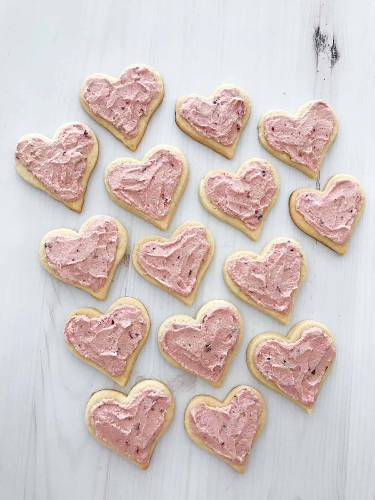 Cream cheese sugar cookies with a pink cherry frosting on a white table 