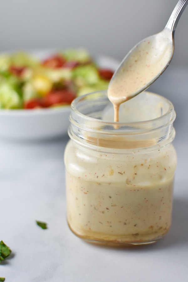 Honey mustard ranch sauce in a mason jar with a spoon dipping into it