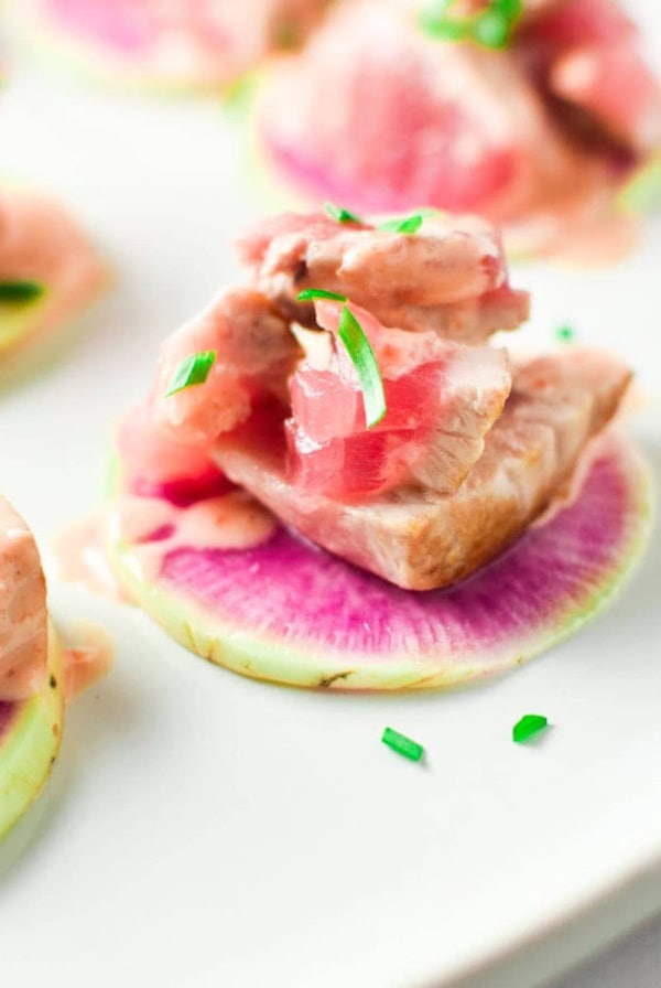 Spicy Tuna mix on top of a watermelon radish with green onion on top