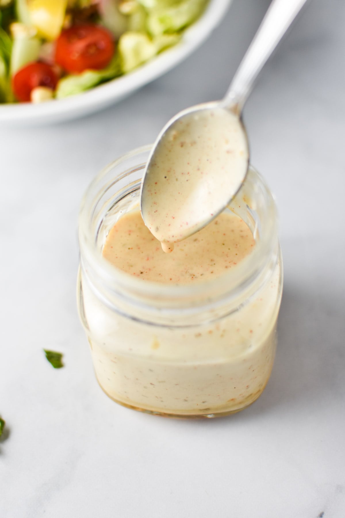 A spoon dipping into a bowl of dressing