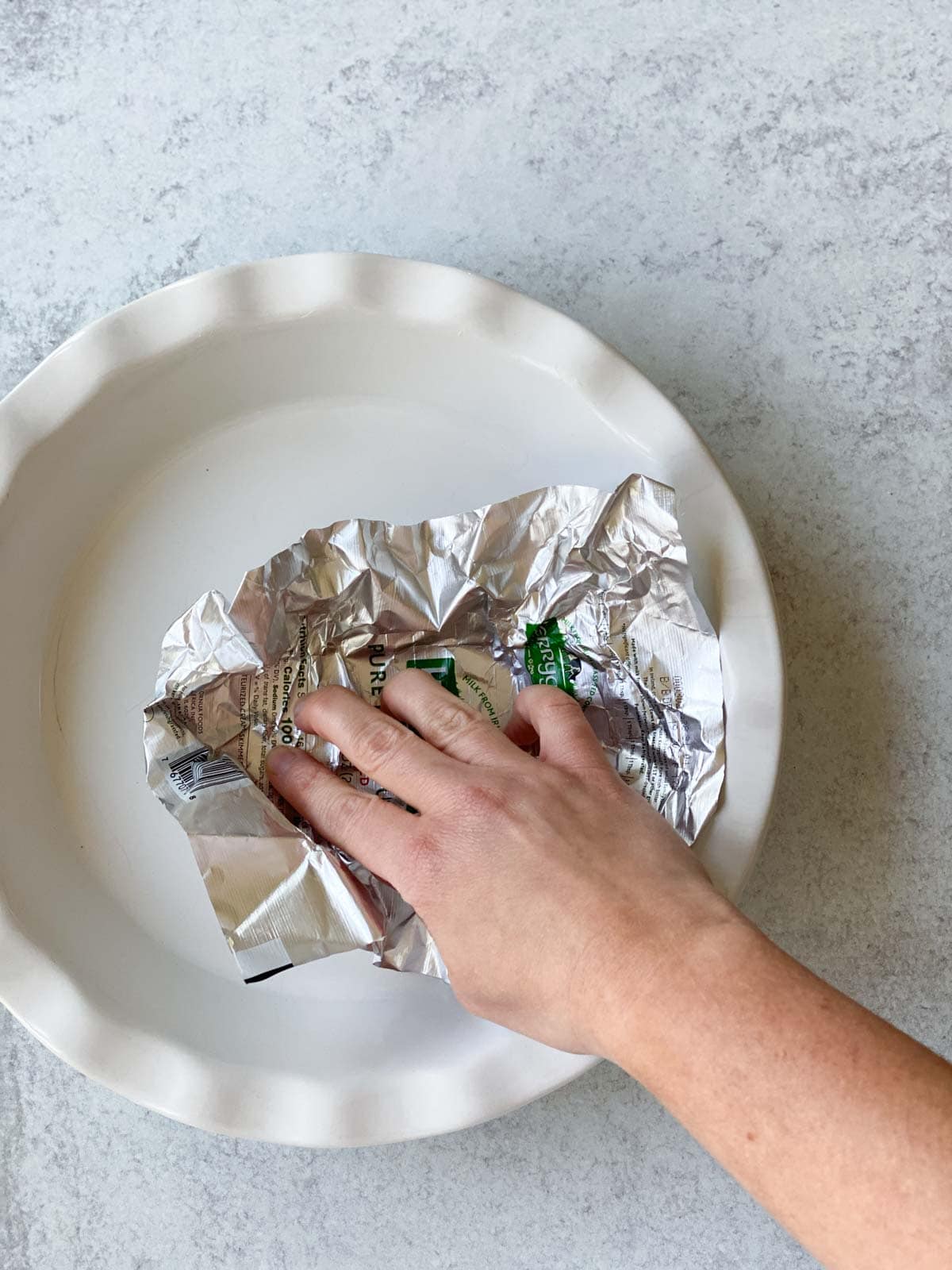 Greasing a pie dish with a butter wrapper.