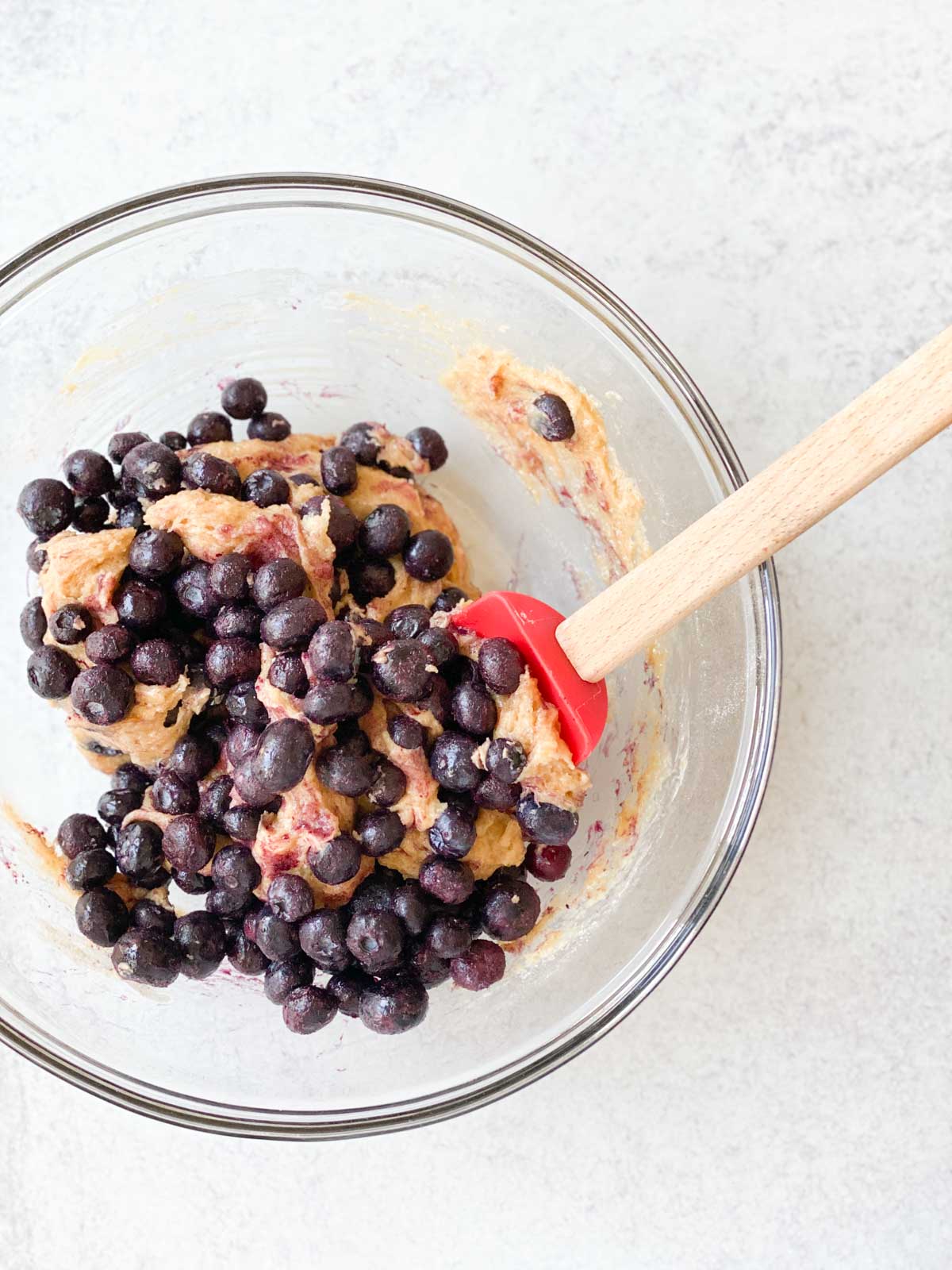 Stirring frozen blueberries into dough.