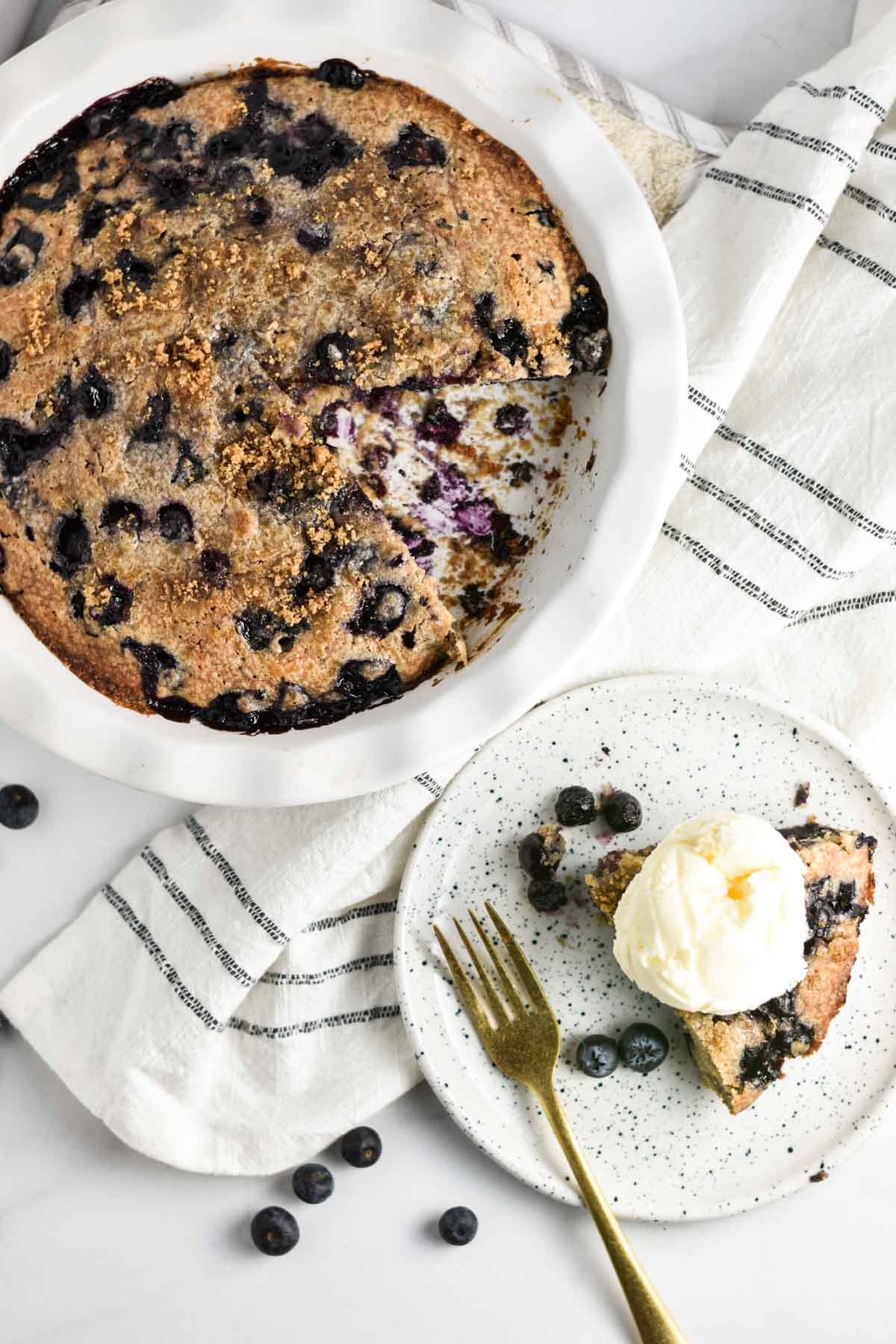 A slice of blueberry pie without crust next to a whole pie dish.