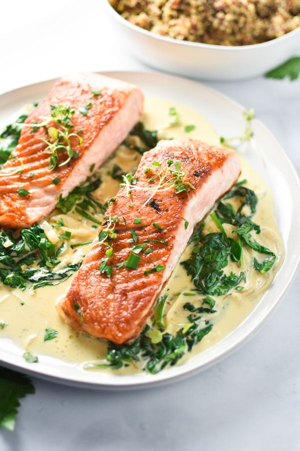 This pan-seared salmon with creamy garlic spinach cooks in one pan and is decadent, yet easy to make. #glutenfree #salmon #easydinner #easyrecipes