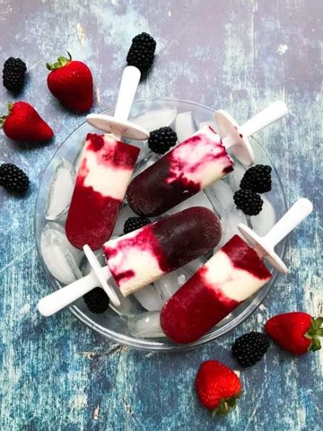 Berry Cheesecake popsicles stacked on a bowl of ice