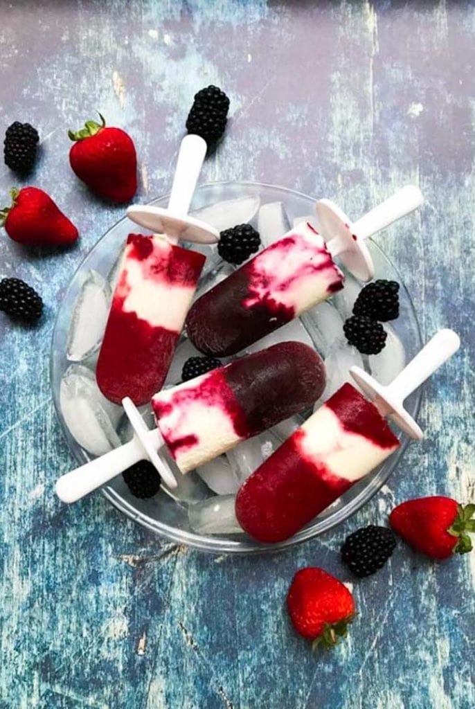 Berry Cheesecake popsicles stacked on a bowl of ice