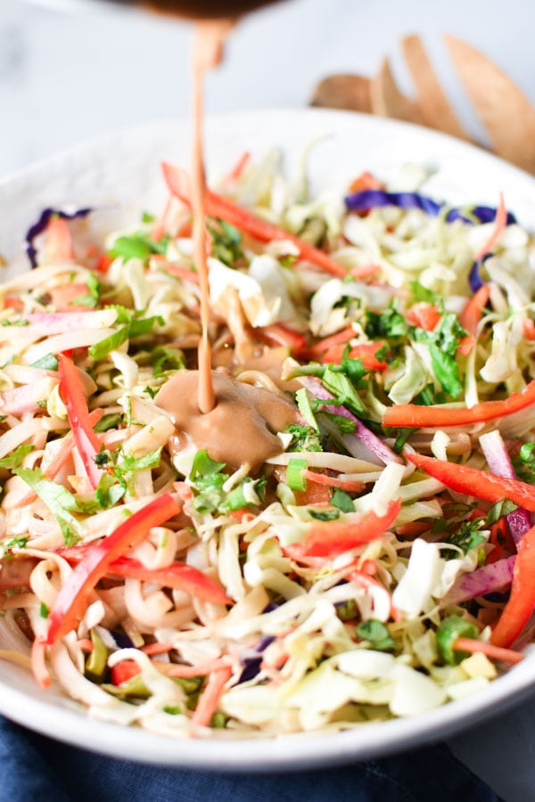 Sunflower seed dressing being poured onto Thai noodle salad