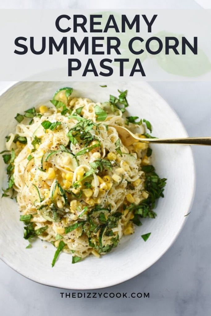 Creamy corn pasta with basil and goat cheese in a bowl with a gold fork