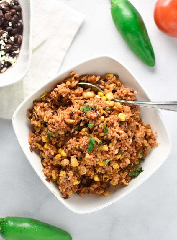 Tomatoes, corn, and rice in a bowl with jalapenos